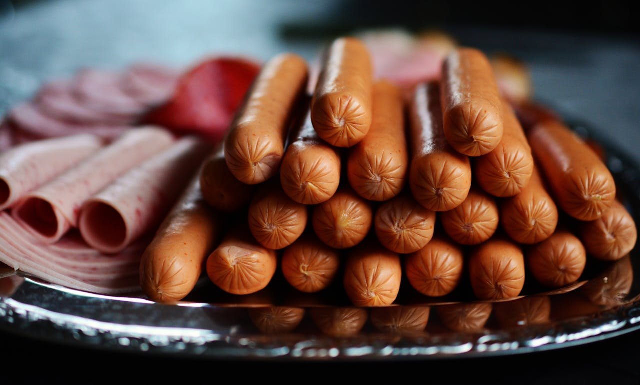 Carnicería en Sort de calidad. Delicious assortment of hot dogs and sliced meats artfully arranged on a silver platter.